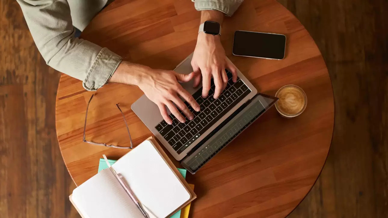 Pessoa digitando em laptop em ambiente de trabalho moderno, representando o uso de copywriting em campanhas de marketing.