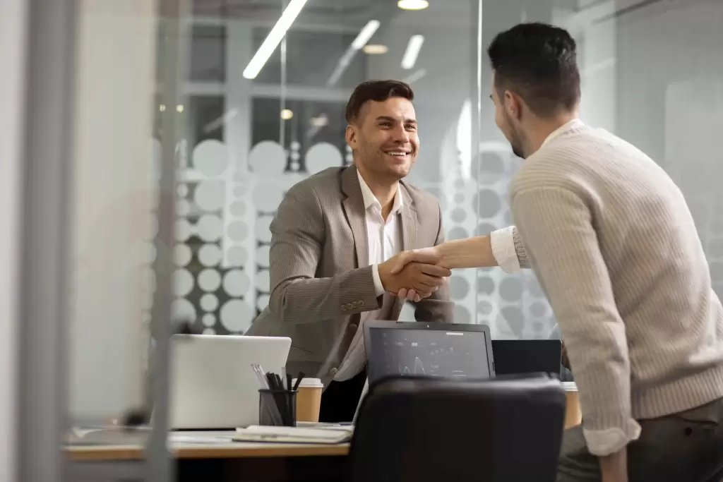Profissional e cliente em reunião de negócios apertando as mãos, simbolizando processo de pré-vendas.