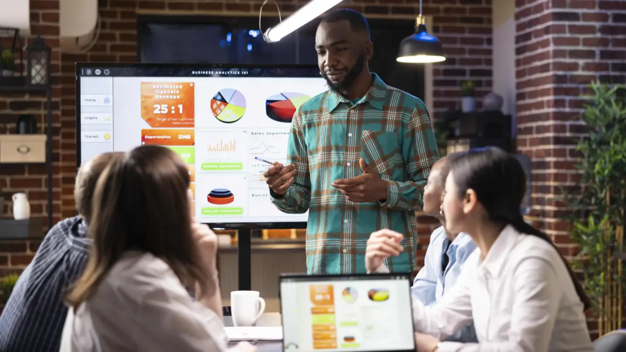 Ferramentas de marketing digital sendo apresentadas em reunião com análise de dados em tela.