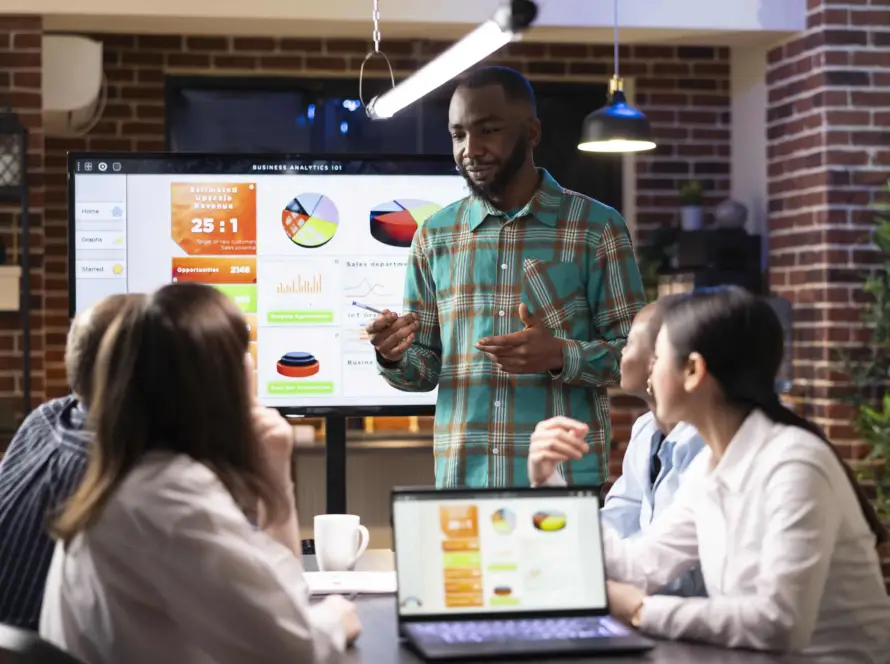 Ferramentas de marketing digital sendo apresentadas em reunião com análise de dados em tela.